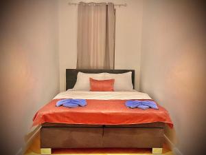 a bed with an orange blanket and a red pillow at Wiedner Apartments in Vienna