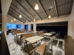 um restaurante vazio com mesas, cadeiras e luzes em Nirved Retreat - A Backwater Forest Stay. 