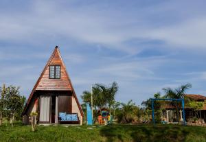 una pequeña casa con un parque infantil en un campo en CHALE DAS ESTRELAS en Piçarras
