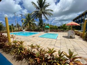 un complejo con 2 piscinas y una palmera en Pousada das Acácias, en Tamandaré