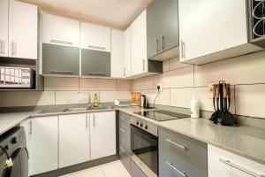 a kitchen with white cabinets and stainless steel appliances at Lovely 2-bedroom apartment, with an amazing view in Durban