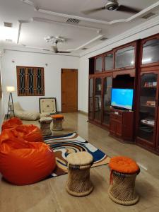 a living room with orange chairs and a flat screen tv at Unpack Hostel in Pondicherry