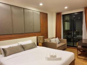 a bedroom with a bed and a couch and a desk at The Astra Suites in Chiang Mai