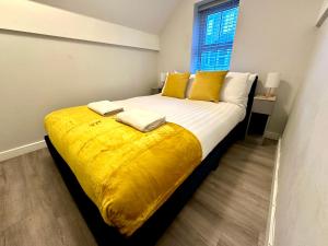 um quarto com uma cama grande com lençóis amarelos e uma janela em Urban Retreat - Close To Town and Beach em Bournemouth