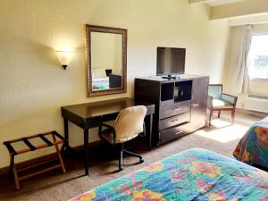 a hotel room with a desk and a mirror at Metro Inn & Suites in Jacksonville