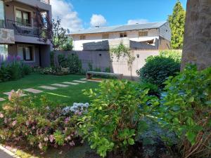 einen Garten mit einer Bank vor einem Gebäude in der Unterkunft Antón SMAndes in San Martín de los Andes