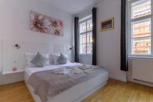 Niva Rooms & Studio Apartment في زغرب: غرفة نوم بيضاء مع سرير كبير مع نافذتين