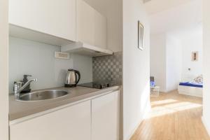 Niva Rooms & Studio Apartment في زغرب: مطبخ مع دواليب بيضاء ومغسلة
