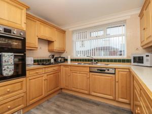 a kitchen with wooden cabinets and a large window at Avon Croft Cottage in Hawsker