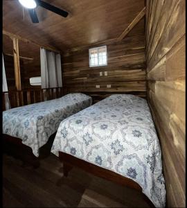 1 dormitorio con 2 camas en una cabaña de madera en Las cabañas del Francés, en Alto Boquete