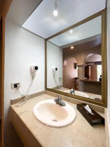 a bathroom with a sink and a large mirror at Hotel Gran Plaza & Convention Center in Guanajuato