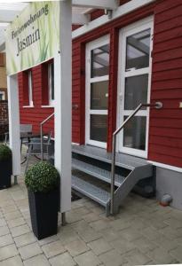 - un bâtiment rouge avec une terrasse couverte et un panneau sur celle-ci dans l'établissement Ferienwohnung Jasmin, à Rust