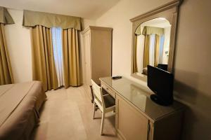 a bedroom with a desk with a television and a bed at Hotel Bristol in Trieste