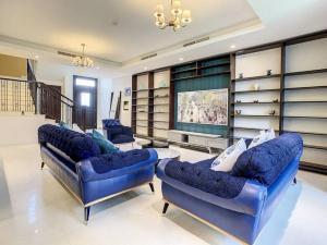 a living room with two blue couches and a television at Key View - Villa, Casa Flores in Dubai