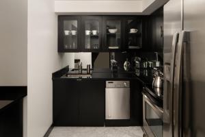 La cuisine est équipée de placards noirs et d'un réfrigérateur en acier inoxydable. dans l'établissement The Manhattan Club, à New York