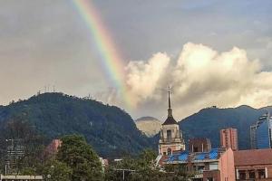 a rainbow in the sky over a city with a building at La Cangreja Casa Biosferista in Bogotá