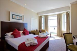 a hotel room with a large bed with red pillows at Bournemouth East Cliff Hotel, Sure Hotel Collection by BW in Bournemouth