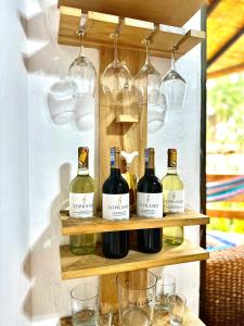 un estante con botellas de vino y vasos. en La Cabaña de Victor, en Olón