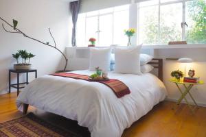 una camera da letto con un grande letto bianco con cuscini bianchi di Comfort Mérida By The Local Way a Città del Messico