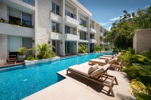 トゥルムにあるNHOA 307B Lux 1BR Condo Pool View in Aldea Zamaのラウンジチェア付きのスイミングプールが隣接しています。