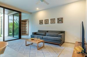 a living room with a blue couch and a table at Selvaterra 201 Lux 2BR Large Condo in Aldea Zama in Tulum