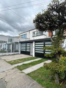 una casa con un garaje blanco y negro en Casa Chimenea a 5 minutos del Aeropuerto, en Bogotá