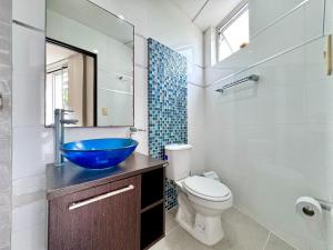 a bathroom with a blue bowl sink and a toilet at HELENE HOUSE in Sincelejo