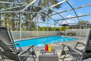 a swimming pool with two chairs and a table at Your Family Fun Villa w Pool, Game room, all you need, close to Disney & more in Davenport