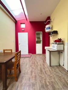 a kitchen with a table and a red wall at PH luminoso en Villa Crespo, a cuadras de plaza Serrano! in Buenos Aires