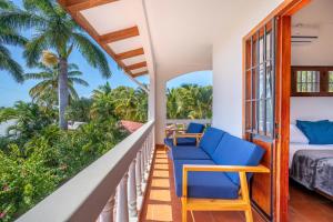 a balcony with blue chairs and a bed and palm trees at Casa Palma Real in Playa Junquillal