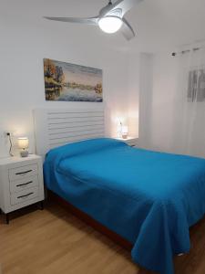 1 dormitorio con cama azul y mesita de noche en El Yate Sol y Mar, en Aguadulce