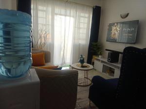 Blissful Lynn's Staycation في نيروبي: غرفة معيشة مع مزهرية زجاجية على طاولة