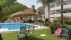 een groep ligstoelen en een parasol naast een zwembad bij Carihuela Plaza del Remo in Torremolinos