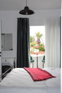 a bedroom with a bed and a window with a table and chairs at BADEMİÇİ OTEL in Alaçatı