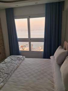 a bedroom with a bed and a large window at شقة فاخرة مكيفة تري البحر مباشرة in Alexandria