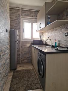 eine Küche mit einer Waschmaschine, einer Spüle und einem Kühlschrank in der Unterkunft شقة فاخرة مكيفة تري البحر مباشرة in Alexandria