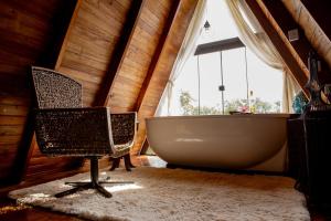 uma casa de banho com banheira e 2 cadeiras em frente a uma janela em Chalé Sunset em Piçarras