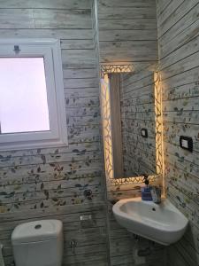ein Bad mit einem Waschbecken, einem WC und einem Fenster in der Unterkunft شقة فاخرة مكيفة تري البحر مباشرة in Alexandria