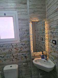 ein Badezimmer mit Waschbecken und Toilette und einem Fenster in der Unterkunft شقة فاخرة مكيفة تري البحر مباشرة in Alexandria