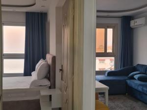 Habitación con cama, sofá y ventanas. en شقة فاخرة مكيفة تري البحر مباشرة, en Alejandría