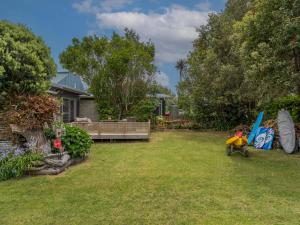 a yard with a house and a backyard with a playground at Kon Tiki Retreat - Whiritoa Beach Holiday Home in Whiritoa