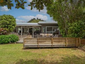 a house with a wooden fence in the yard at Kon Tiki Retreat - Whiritoa Beach Holiday Home in Whiritoa