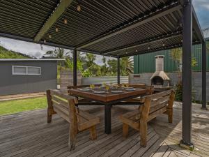 a wooden deck with a table and two benches at Kon Tiki Retreat - Whiritoa Beach Holiday Home in Whiritoa