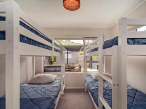 a bedroom with two bunk beds and a balcony at Kon Tiki Retreat - Whiritoa Beach Holiday Home in Whiritoa