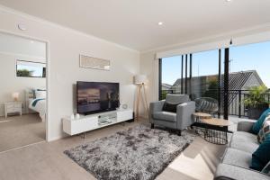 uma sala de estar com uma televisão, um sofá e uma cadeira em Luxury Apartment retreat em Tauranga