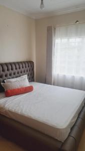 Una cama con una almohada roja encima. en Greenview Homes en Eldoret