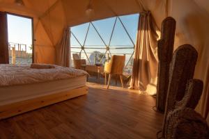 um quarto com uma cama, uma mesa e uma grande janela em Timlalin Dome em Tamri