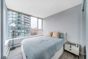 a white bedroom with a bed and a large window at Amazing Views ! Leather Furniture ! Cozy Condo! in Vancouver