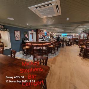 un restaurante con mesas y sillas de madera y un bar en Blue Door Apartment Main St, Carrigart, F92HC04 en Carrigart