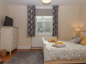 a bedroom with a bed with a dresser and a window at Mimosa in Dawlish